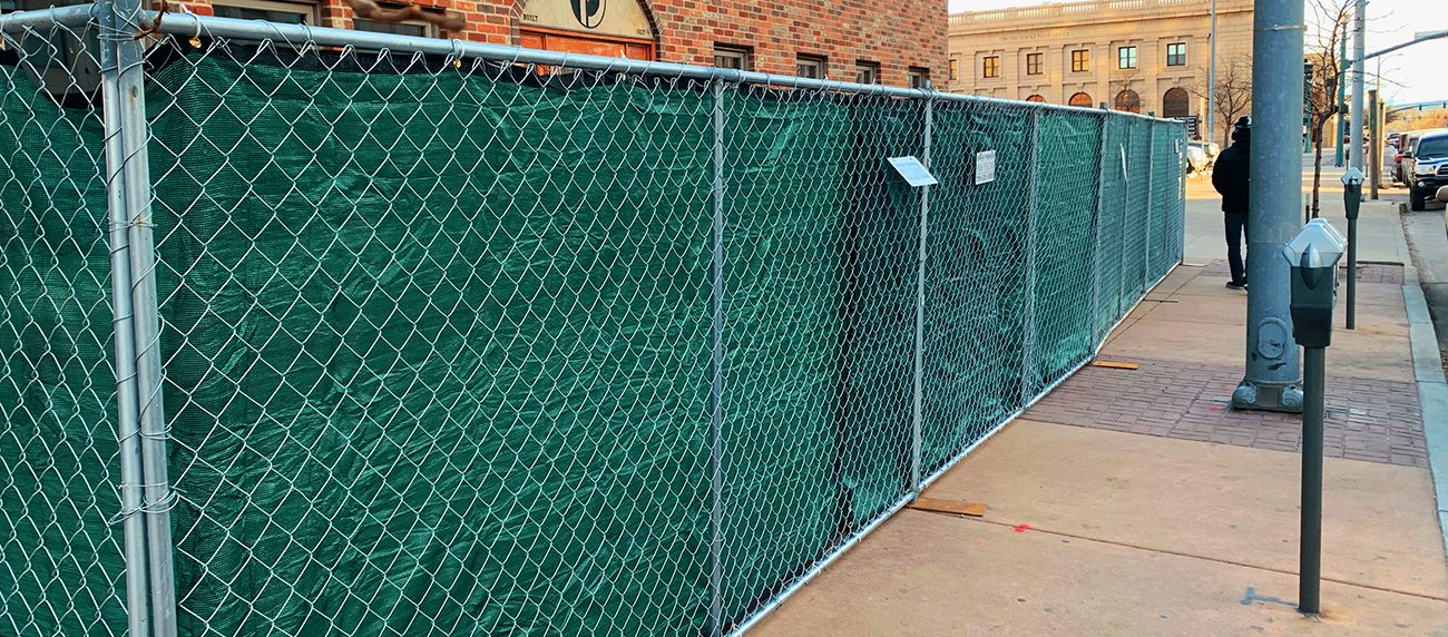 Temporary chain link fence panels with green screen on a city sidewalk