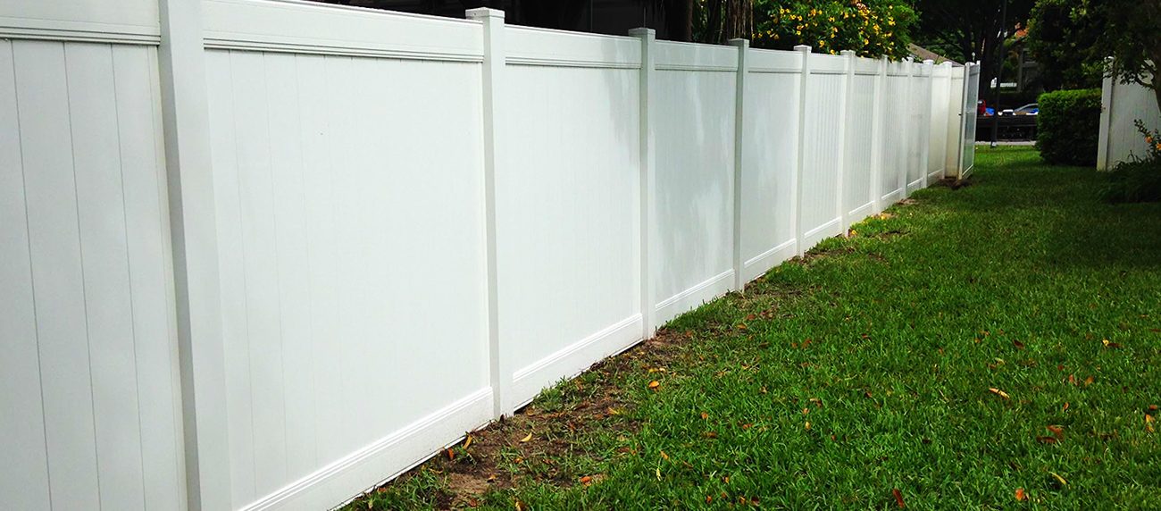 White vinyl privacy fence along a lawn